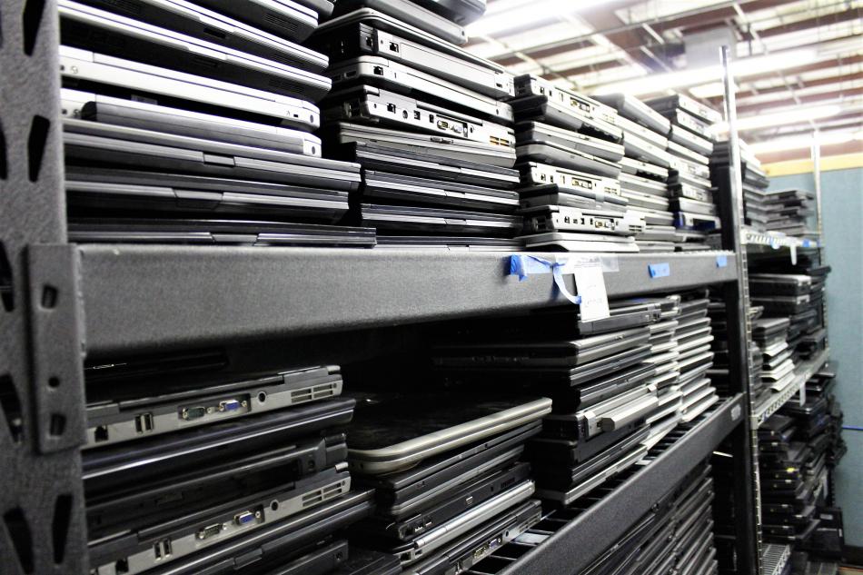 Laptops are stacked high on shelves at ComputerCorps.