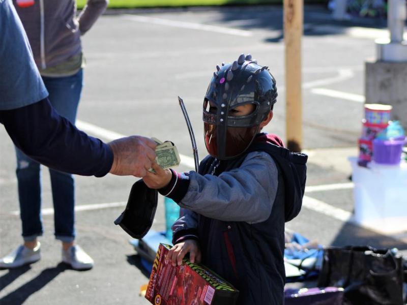 Photos by Brett Fisher. A child in costume purchases a toy at the Community Garage Sale.