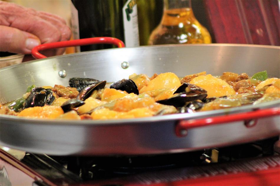 Fresh prepared Paella cooks in a skillet.