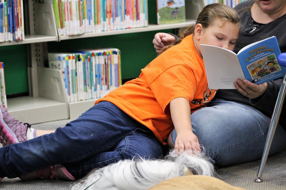 A child pets a therapy dog Saturday while reading at the Carson City Library.