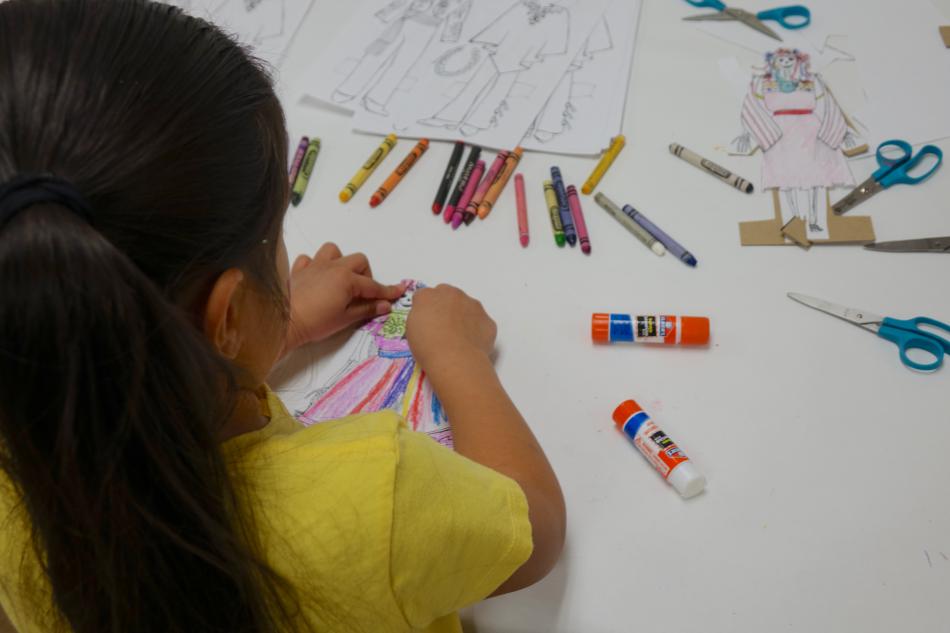 A girl puts the finishing touches on her paper doll.
