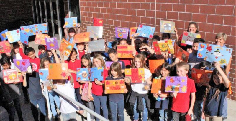 Students from fourth grade classes show off their hand-made placemats created for seniors. Click photo for full size