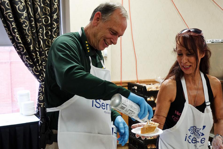 Carson City Sheriff Kenny Furlong adding whipped cream to a slice of pie