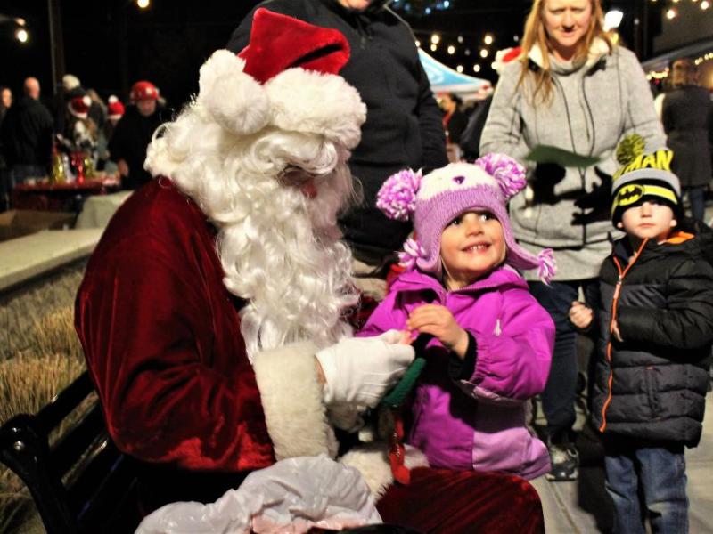 Santa Claus gives a little girl a candy cane in Bob McFadden Plaza Friday night.