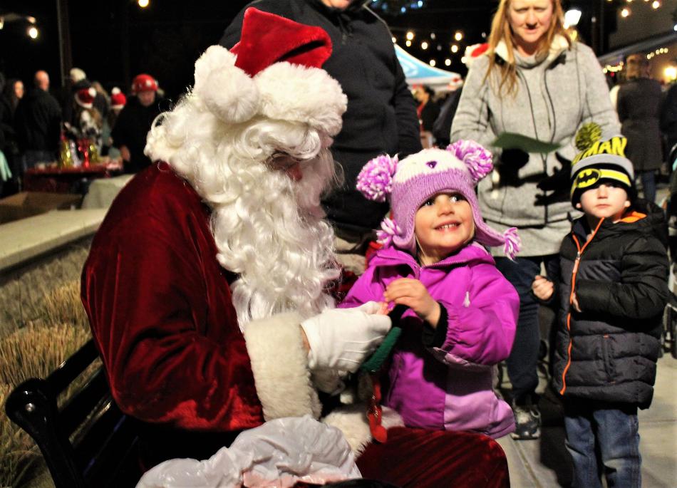 Santa Claus gives a little girl a candy cane in Bob McFadden Plaza Friday night.