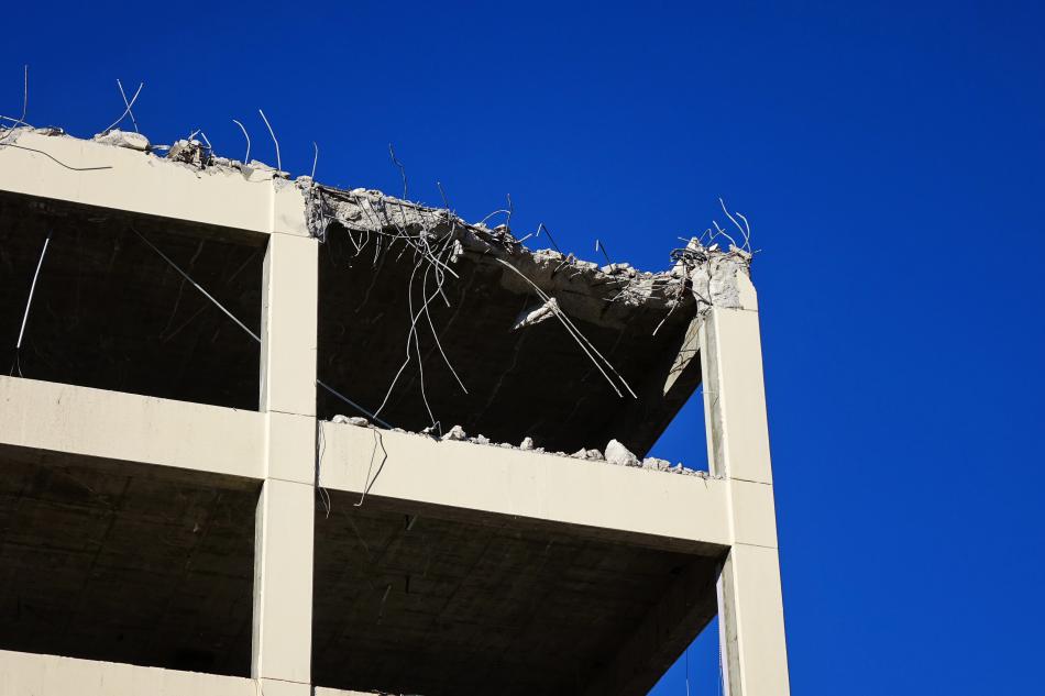 The excavator removes chunks of concrete and metal working from the top floor down.