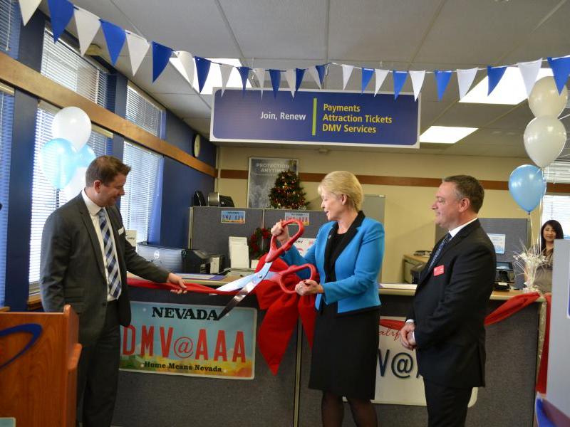 DMV Director Terri Albertson cuts the ribbon alongside AAA's Brian MacAdam and John Cruger.