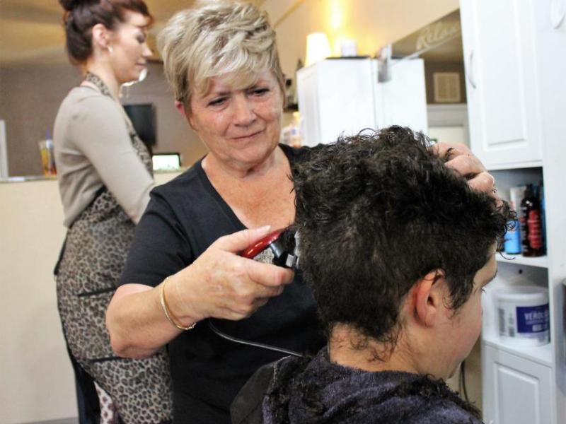 Photos by Brett Fisher. A boy gets his hair cut Saturday during a fundraiser event for the Schmidt family.