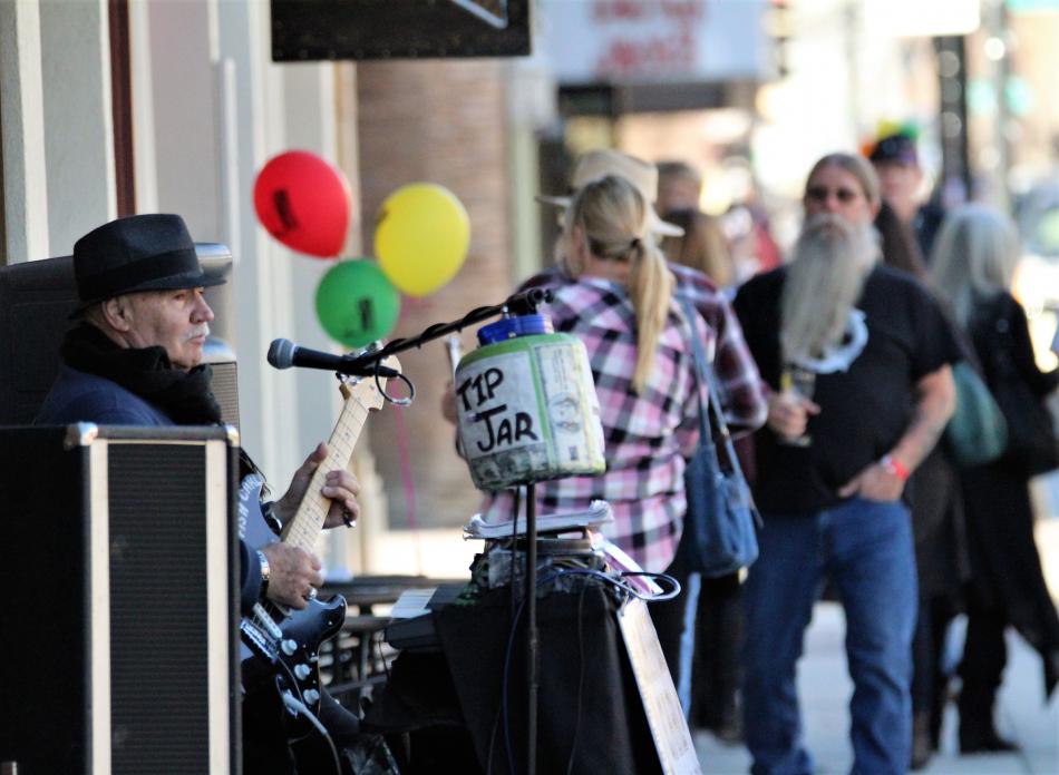 Photo by Brett Fisher. A musician strums his guitar for downtown visitors during the Saturday Wine Walk.