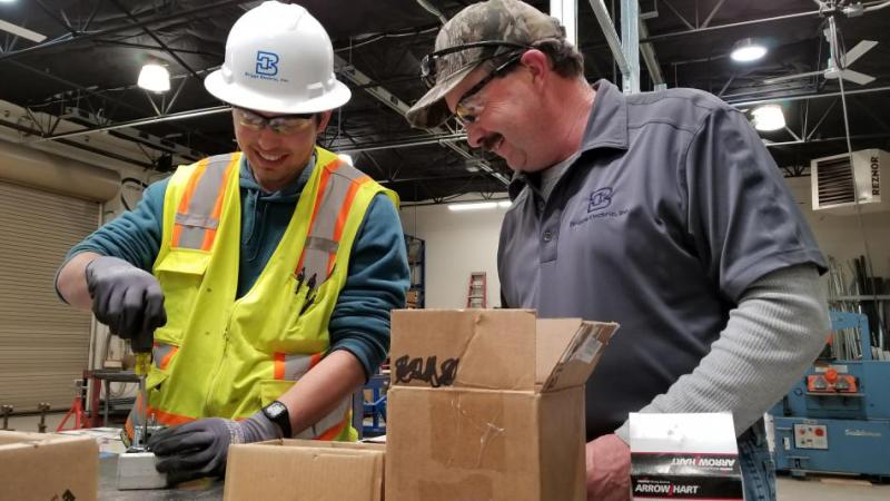 Arturo Ortiz works with Bob Seymour, field superintendent for Briggs Electric in company’s shop.