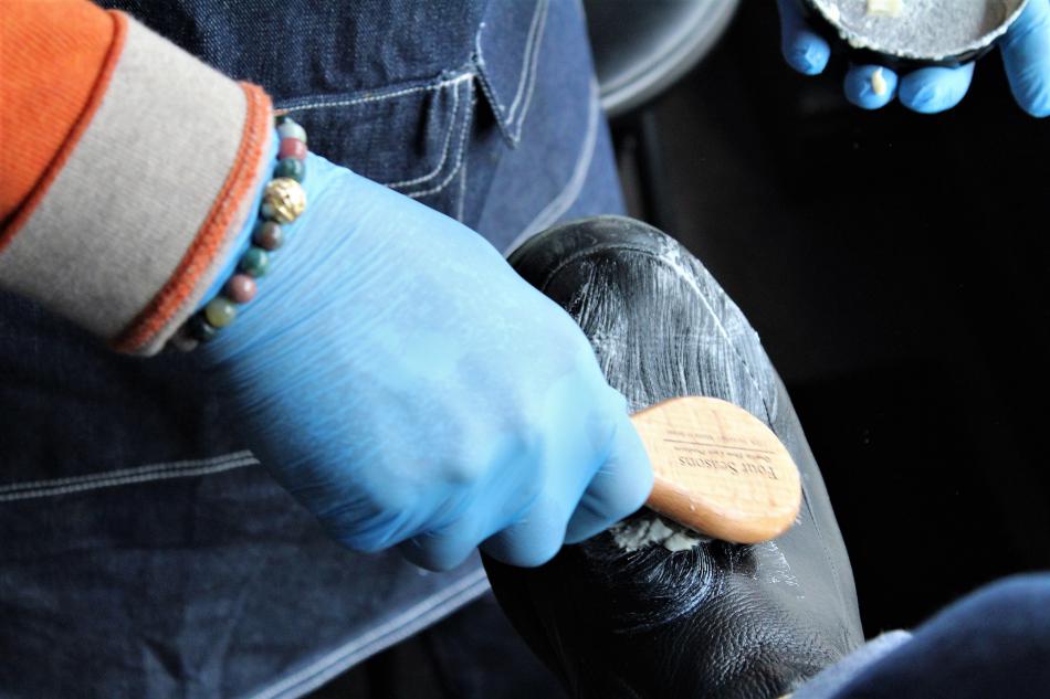Smith scrubs a leather shoe with cleaner.