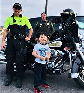 Matthew Ramirez, 3, with Sheriff's deputies and their vehicles.