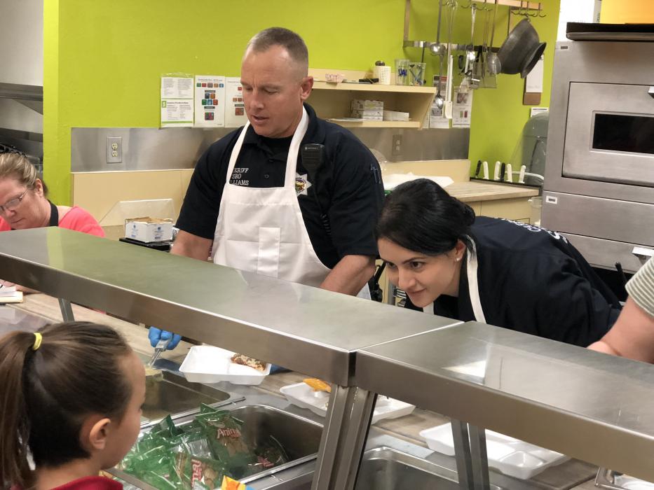 School Resource Officers Dean Williams and Liz Lopez serve breakfast to grade schoolers.