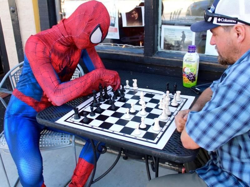Photo by Brett Fisher. Spider-Man plays a game of chess Saturday afternoon in front of Comma Coffee.