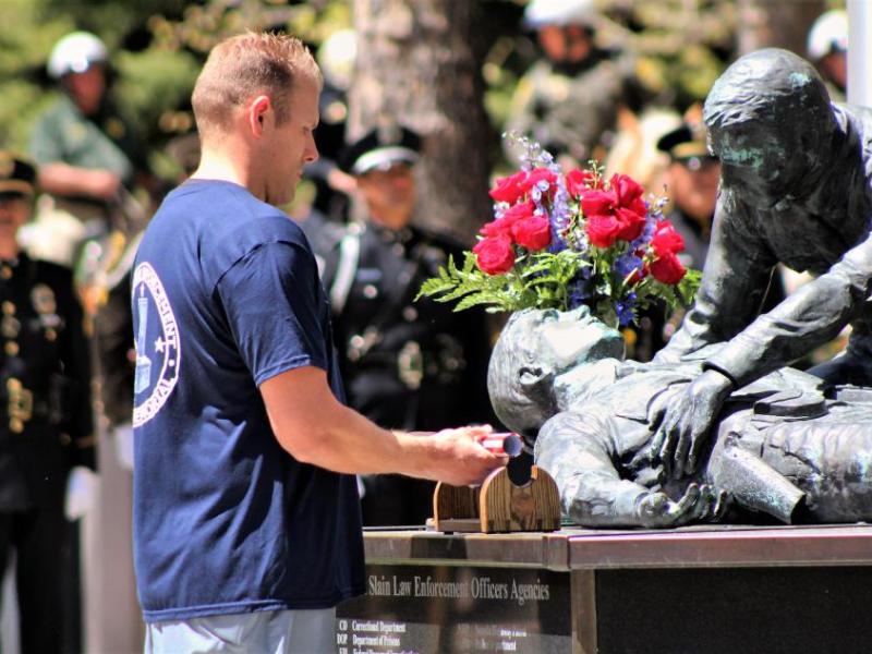 Photos by Brett Fisher. The baton with fallen officer names inscribed on it is placed upon the memorial Thursday.