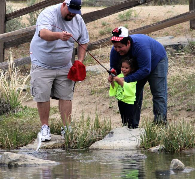 Photos by Brett Fisher. A little girl reels in a fish Saturday at Baily Pond.
