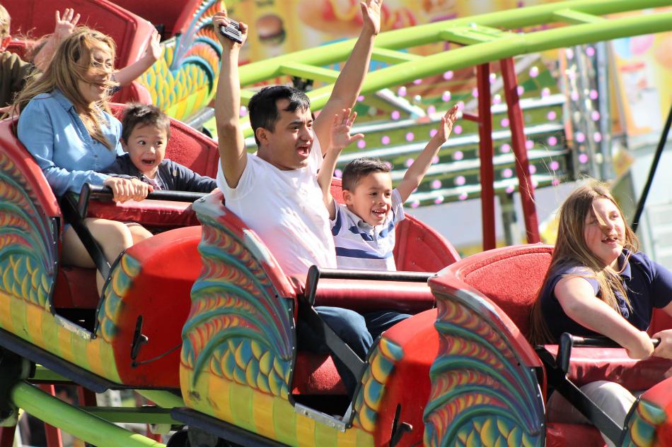 Photos by Brett Fisher. A family enjoys a roller coaster ride at Mills Park.