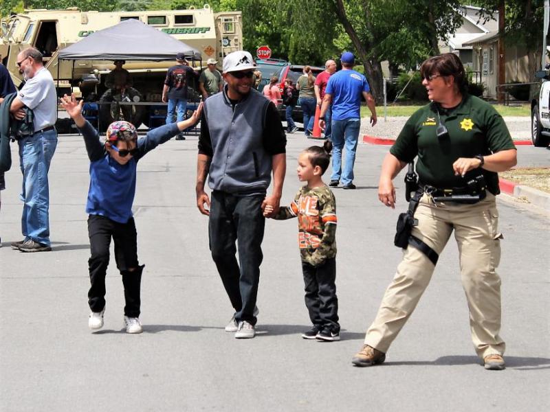 Photos by Brett Fisher. A youth and a Sheriff's deputy dance to music Saturday along East Musser St.