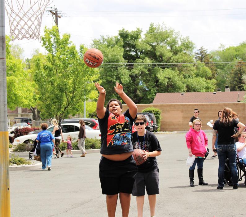 Youth shoot baskets in the parking lot at the corner of Harbin and Musser streets.