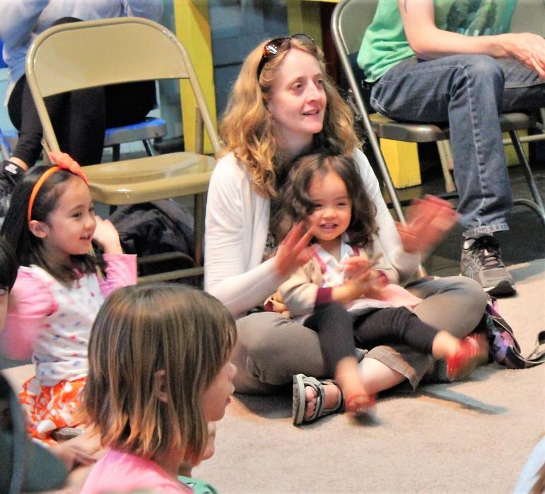 A child and her mother clap to music by Purly Gates.