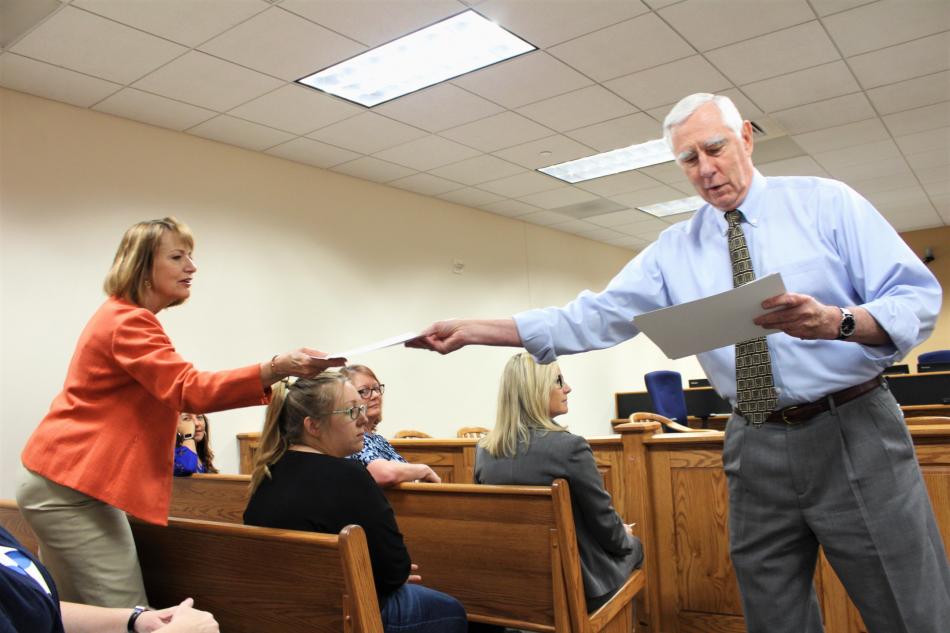 First Judicial District Court Judge James T. Russell hands a signed certificate to a guardian ad litem.