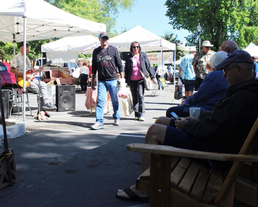 Visitors listen to live music Saturday at the Third and Curry Farmer's Market.