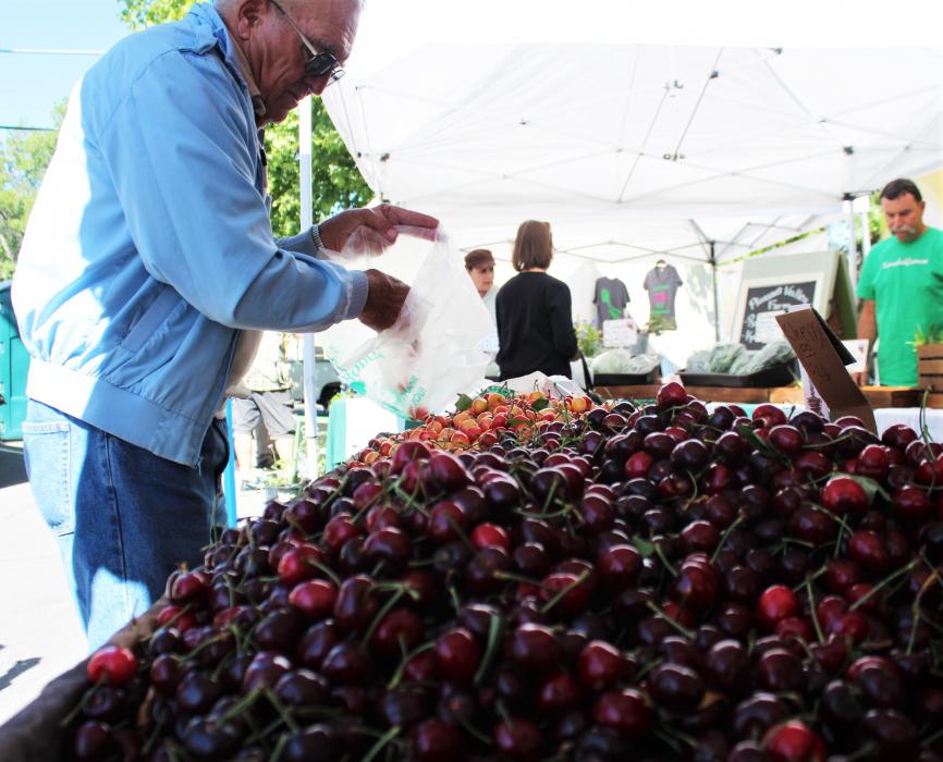 A customer bags cherries Saturday at the Third and Curry Farmer's Market.