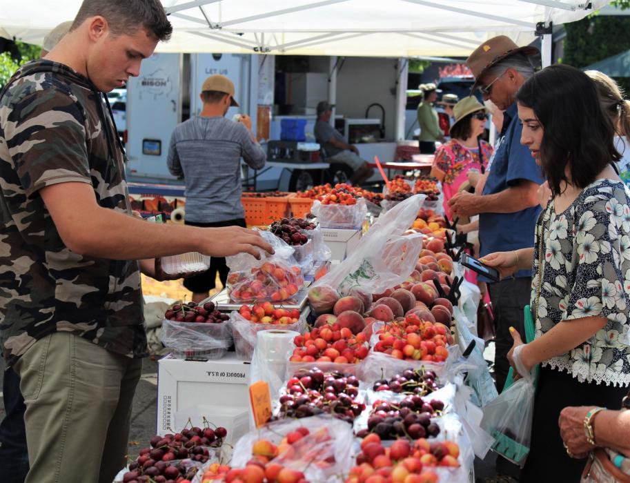 A vendor bags produce for a customer Saturday at the Third and Curry Farmer's Market.