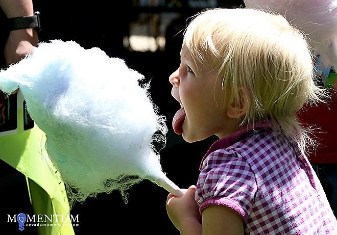 Photos by Shannon Litz/Nevada Momentum. AnnMarie Hansen, 2, tries cotton candy at the Summer Learning Challenge kickoff Sunday.