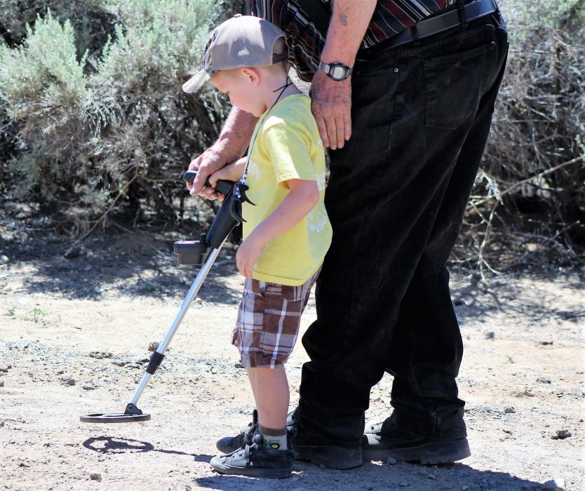 A boy learns how to use a metal detector from an expert Saturday.