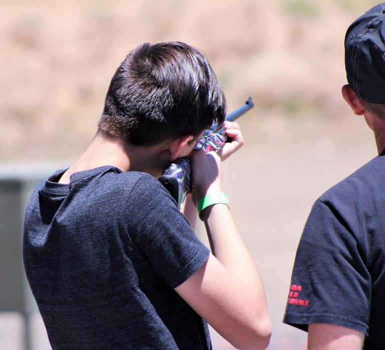 A youth fires an air rifle at a target Saturday, guided by an expert.