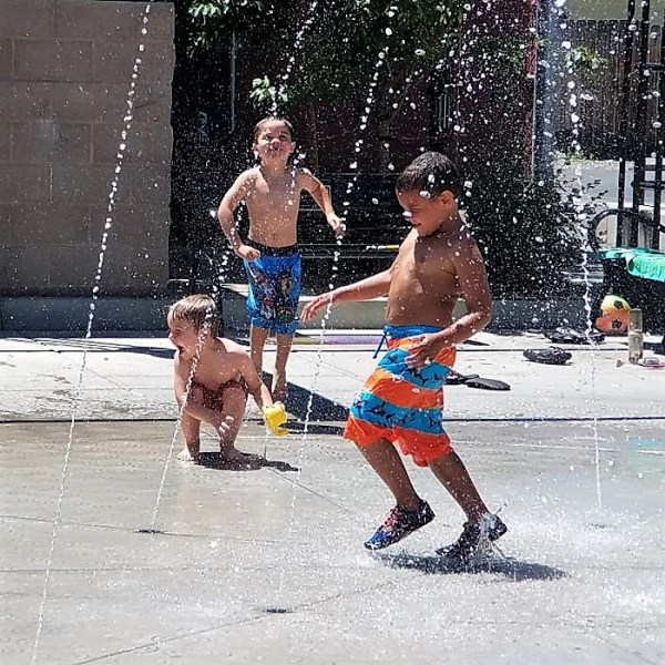 Photos by Brett Fisher. Children cool off in the water fountain on McFadden Plaza Sunday.