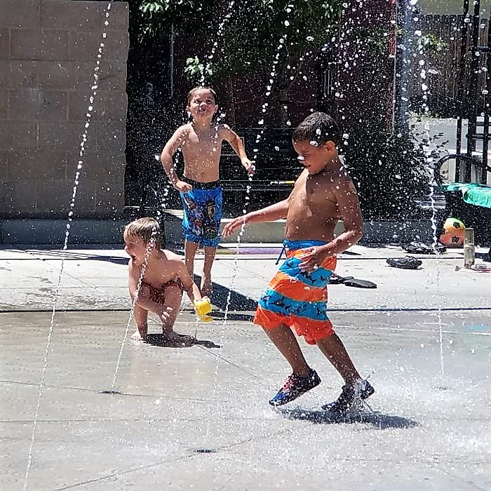 Photos by Brett Fisher. Children cool off in the water fountain on McFadden Plaza Sunday.