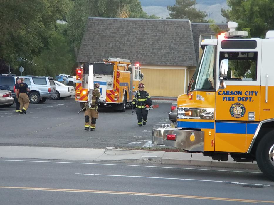 Photo by Brett Fisher. Firefighters carry ladders back to their engine Sunday evening at Carson Sunset Apartments.