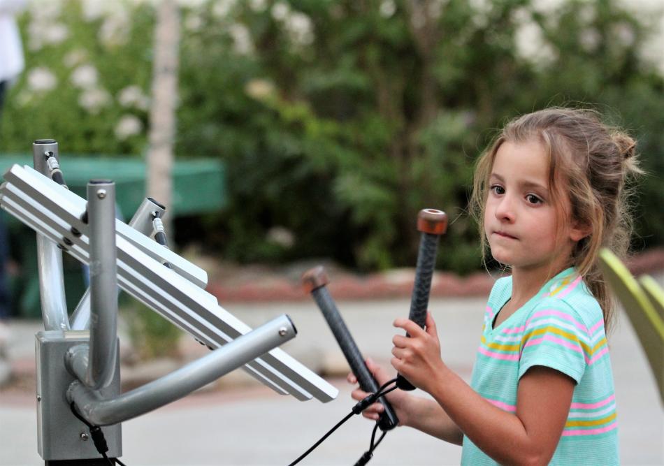 A girl plays on a musical instrument sculpture at the BAC Saturday night.