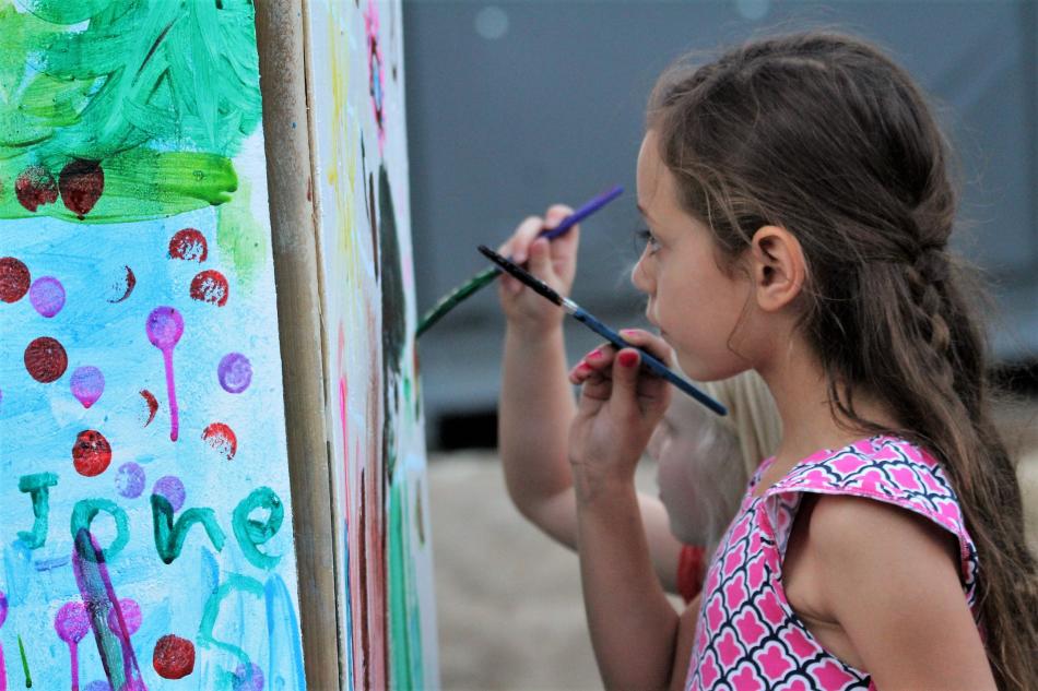 Two girls paint on giant art walls set up at the BAC.