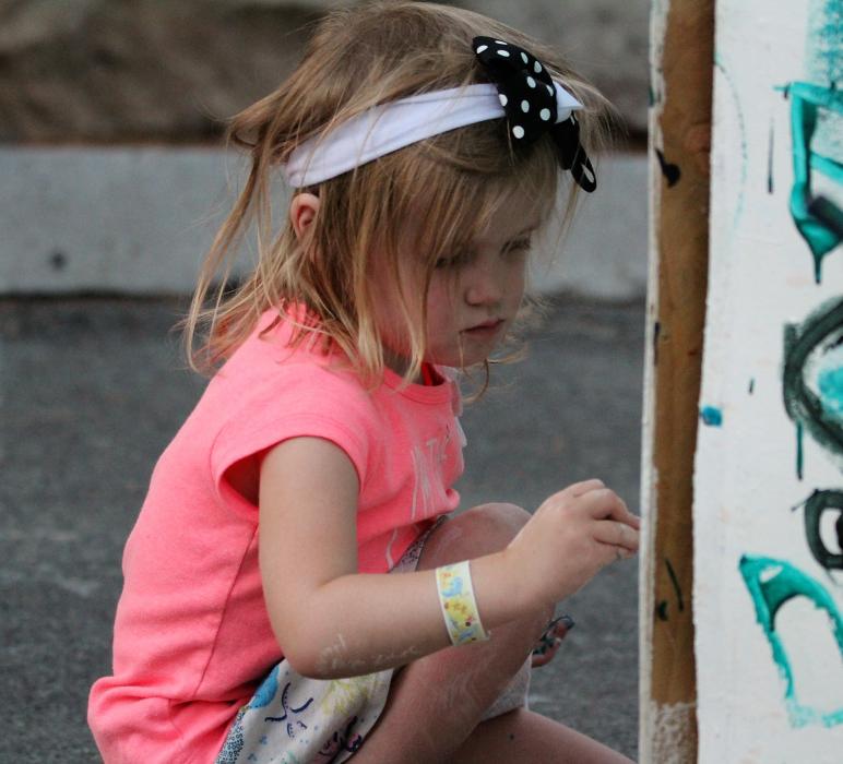 A little girl paints on giant art walls set up at the BAC.
