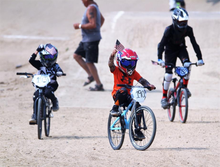 BMX riders wave flags after the opening lap and playing of the National Anthem.