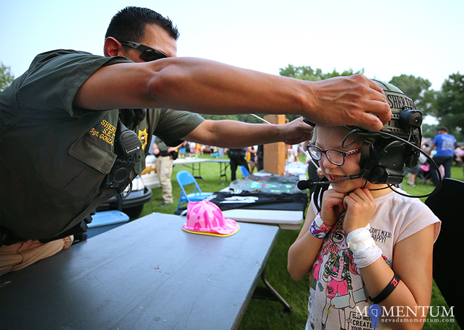 Carson City Sheriff’s Sgt. Daniel Gonzales helps Lyric Adams, 7, try on a SET helmet.