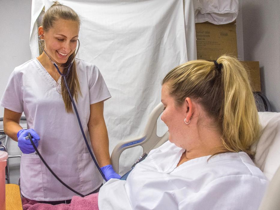 Mackenzie Leis, left, practices lood pressure-taking techniques on Alaina Roseland in a Certified Nursing Assistant class.