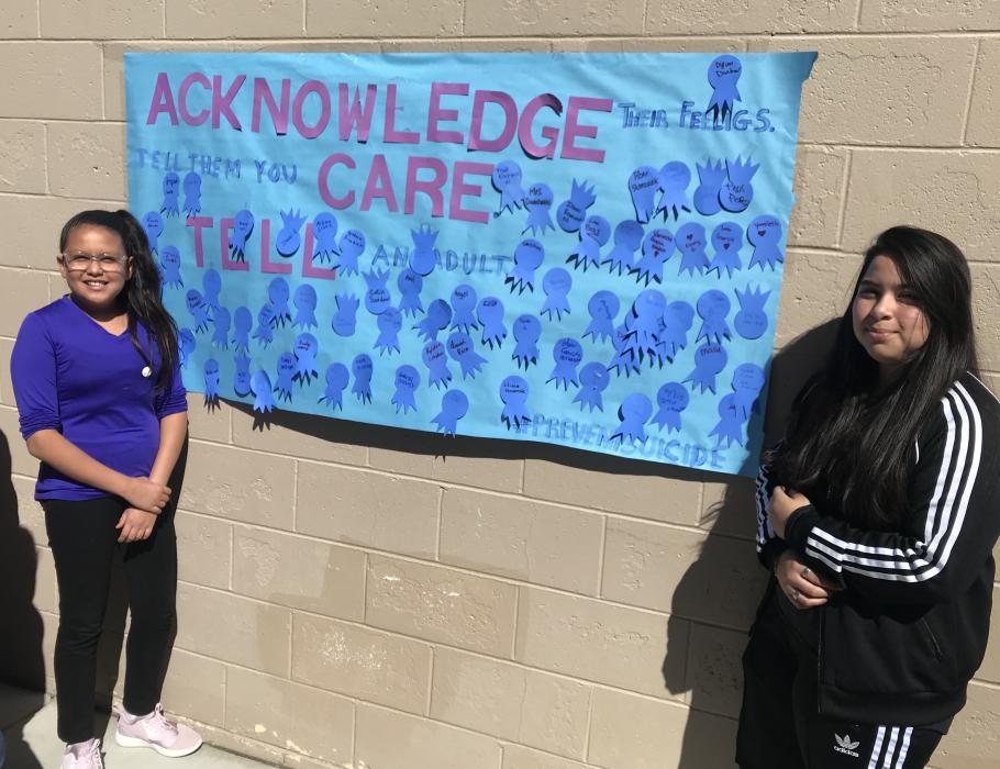 Shania Carrillo and Liliana Navarrete stand beside the pledge board.