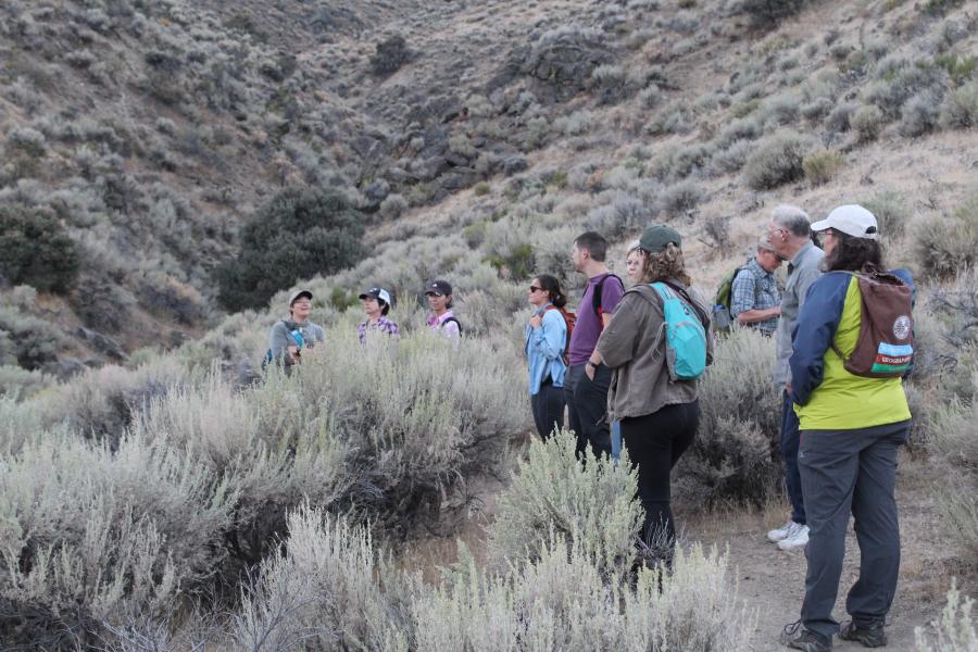 Hikers pausing to enjoy the view of the moon and vegetation of Prison Hil.