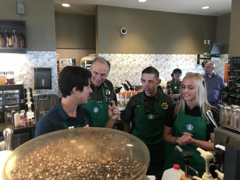 The sheriff and officers poured lattes and took payment at the drive-thru, under the supervision of the Starbucks barista.