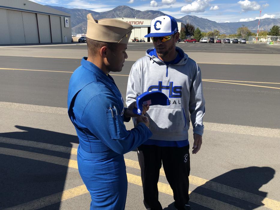 Matt Morgan shakes hands with the US Navy’s Lieutenant Cmdr. Andre Webb after landing and exchanging a CHS baseball cap.
