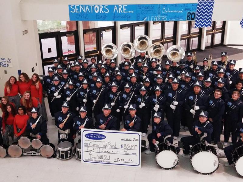 Photo by Brett Fisher. Carson High School's Blue Thunder marching band poses with a check from Capital Ford.
