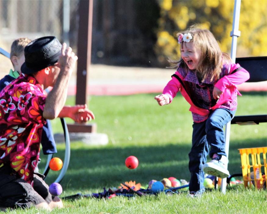 A little girl enjoys a game of ball juggling with a juggler Saturday.