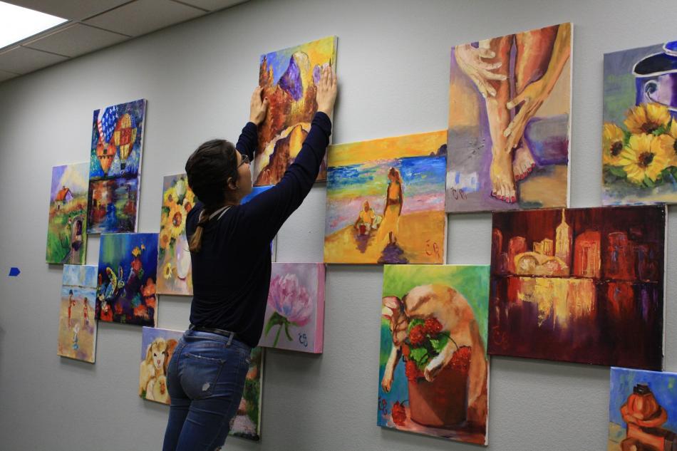 Jazlyn Duran, a senior at CHS, sorts through original oil and acrylic paintings by former Carson artist Carol Benson.