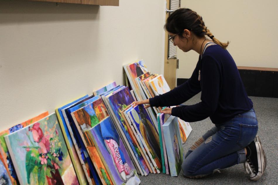 Jazlyn Duran showcases two of hundreds of oil and acrylic paintings donated to the Carson City Senior Center.