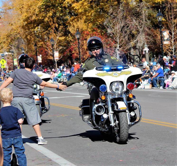 Photo by Brett Fisher. A CCSO motor officer low-fives a young parade-goer during the 2017 Nevada Day Parade.