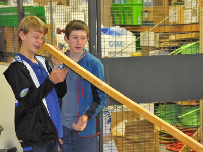 Halen Harrison, left, and Bennett Card check their piece of lumber for warping in their project to build a canoe.